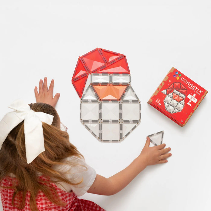 Child building a Santa face from red, peach and clear Connetix tiles