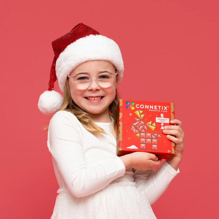 Girl in a Santa hat holding the Connetix Christmas Reindeer Pack box