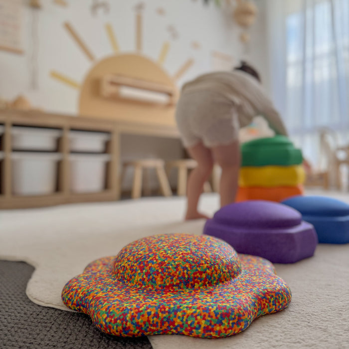 Child stacking Funova stepping stones in a playroom with a confetti balance board in front